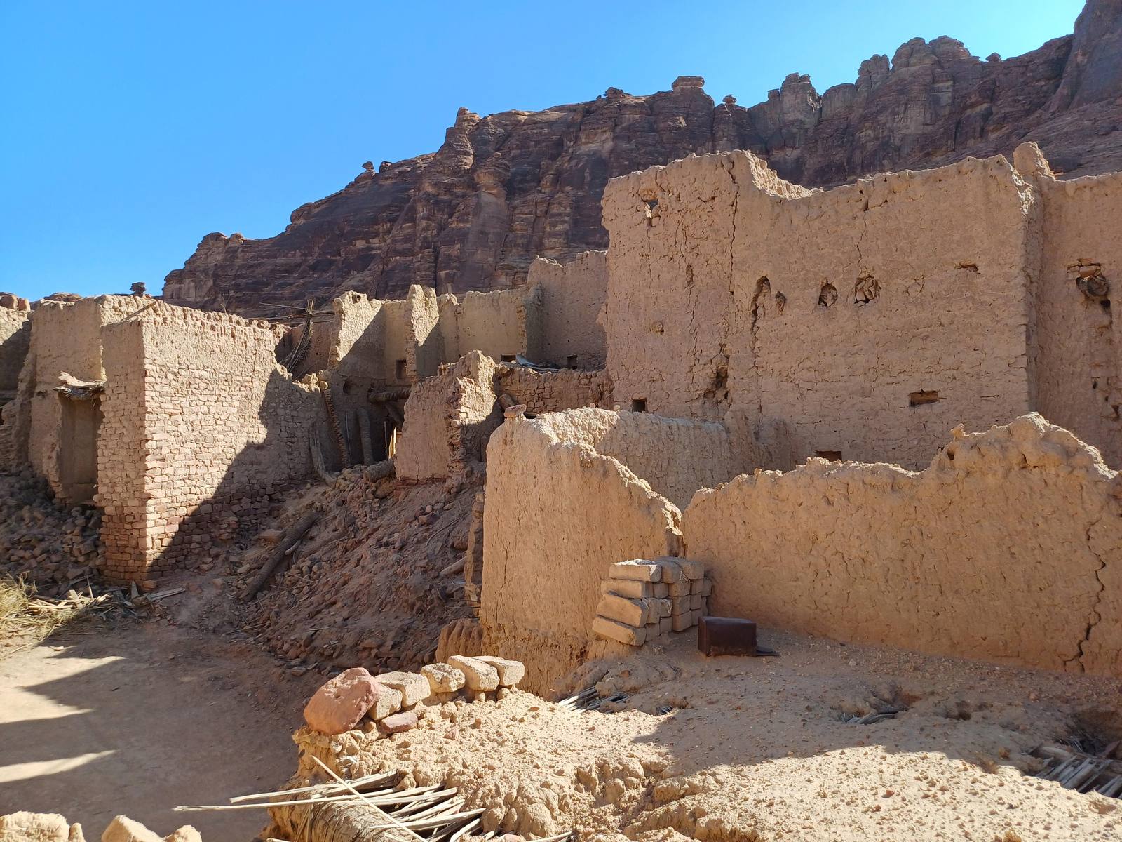 Mud-brick ruins of AlUla Old Town with sandstone cliffs behind