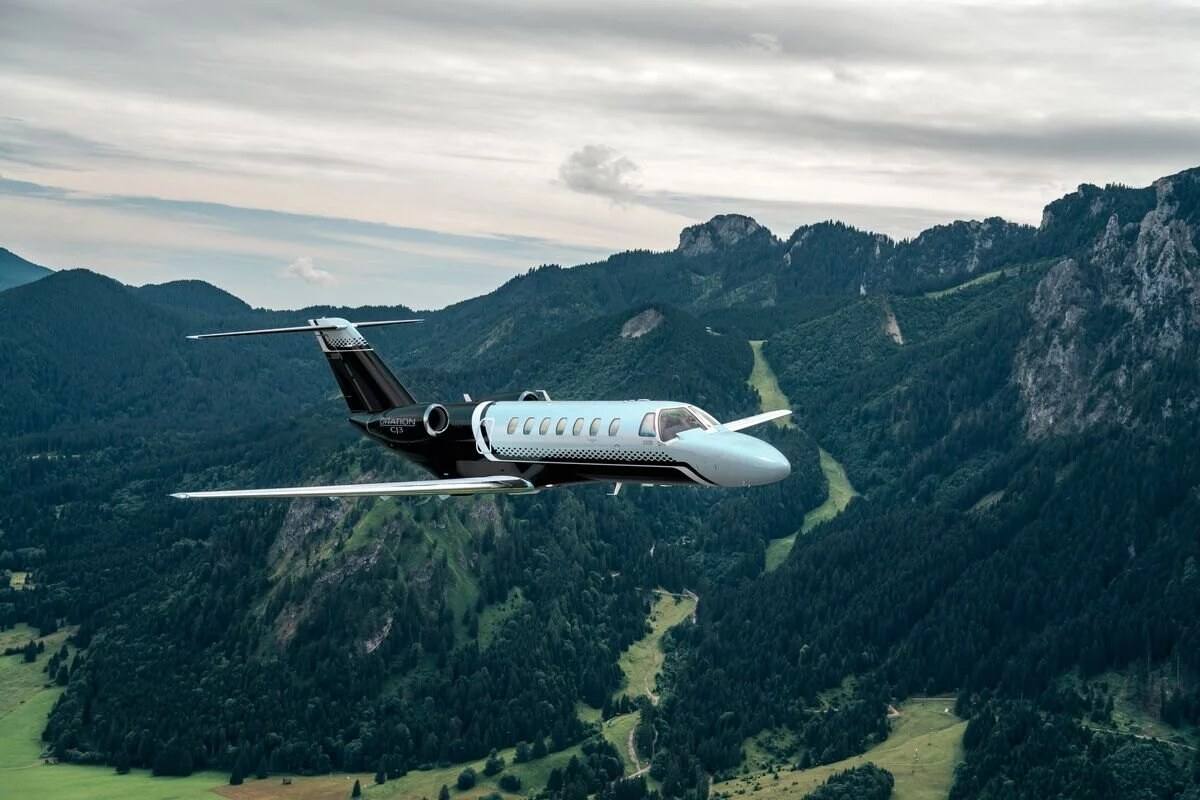 A Cessna Citation CJ3 Gen2 in flight over forested mountains